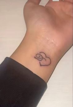 a woman's wrist with a small heart tattoo on the left side of her arm