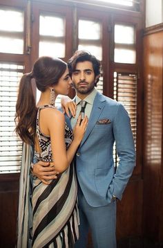 a man in a blue suit and tie standing next to a woman wearing a striped dress