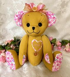 a brown teddy bear sitting next to pink flowers