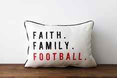 a pillow with the words faith family football on it sitting on a wooden table next to a white wall