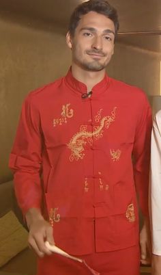 a man and woman standing next to each other wearing red clothing with dragon designs on them