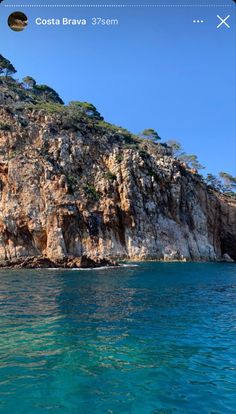 the water is crystal blue and there are many trees on top of this mountain in costa brava