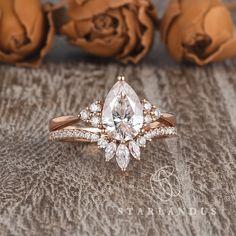 an engagement ring set with a pear shaped diamond surrounded by smaller diamonds and rose petals