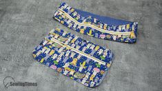 two blue and yellow purses sitting on top of a cement floor next to each other