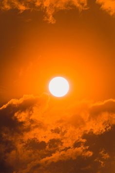 an airplane flying in the sky at sunset with bright orange and yellow clouds behind it