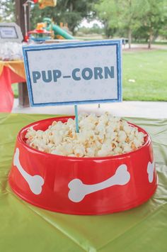 a red bowl filled with popcorn sitting on top of a green tablecloth covered field