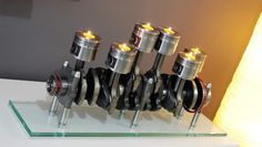 a group of engine parts sitting on top of a glass table next to a lamp