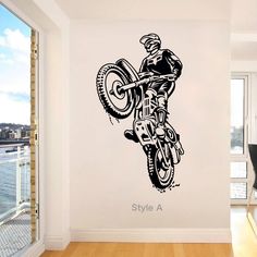 a man riding a motorcycle on top of a wooden floor in front of a window