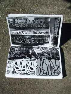 an open box with graffiti on it sitting on the ground next to a black and white photo