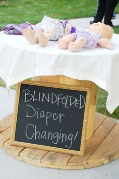 a sign that says blind folded diaper changing on top of a table with stuffed animals