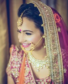 a woman in a pink and orange bridal outfit with gold jewelry on her face