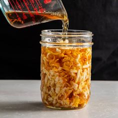 a person pouring some liquid into a jar filled with shredded onions on top of a table