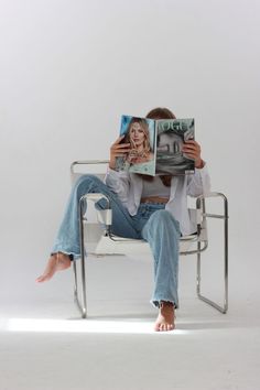 a woman sitting in a chair reading a magazine