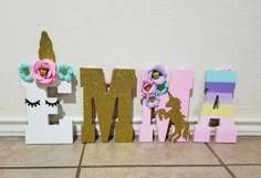 the letters are decorated with flowers and unicorns on them in front of a wall