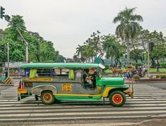 an old green and yellow bus driving down a street next to palm tree covered trees