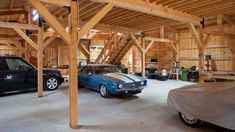 several cars are parked in a garage with wood beams on the ceiling and wooden walls