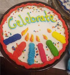 a birthday cake decorated with colorful candles and the words celebrate on it's frosting