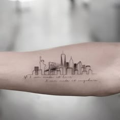 a person's arm with a city skyline tattoo on it