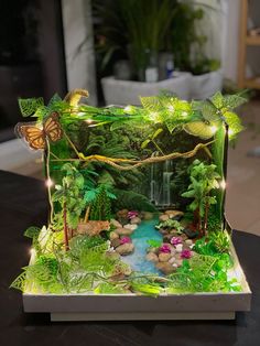 a model of a waterfall surrounded by greenery and fairy lights on a table in a living room