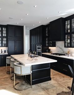 a large kitchen with black cabinets and marble counter tops