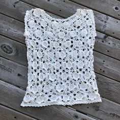 a white crocheted top sitting on top of a wooden floor