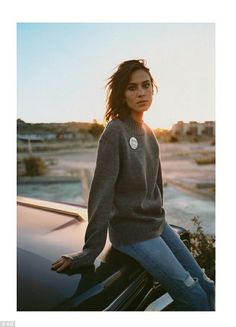 a woman sitting on the hood of a car