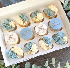 a box filled with blue and white cupcakes on top of a wooden table