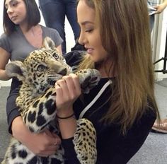 a woman holding a baby leopard in her arms