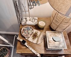 a wooden table topped with lots of items next to a lamp and a wall mounted clock