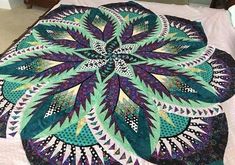 a bed topped with a green and purple quilt