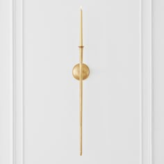 a golden door handle on the side of a white door with a gold stick sticking out of it