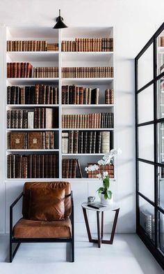 a leather chair sitting in front of a book shelf filled with books