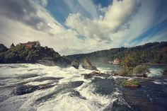 a river with rapids and houses in the background