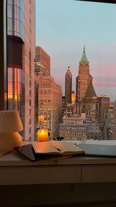 a window with a view of the city at dusk from it's windowsill