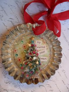 a christmas ornament with a red ribbon on it and a small tree in the center