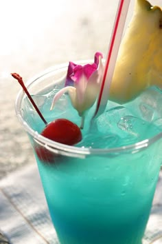 a blue drink with a cherry on the rim and garnished with a flower