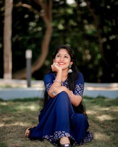 a woman sitting in the grass with her hand on her chin