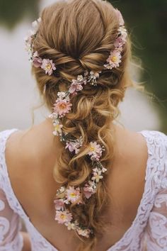 the back of a woman's head, with flowers in her hair and an intricate braid