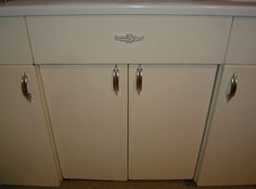 an old fashioned kitchen with white cabinets and silver knobs on the front door handles