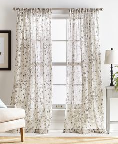 a living room with a couch, chair and window covered in white sheer curtaines