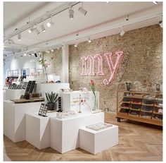 the interior of a clothing store with pink neon signs on the wall and wooden floors