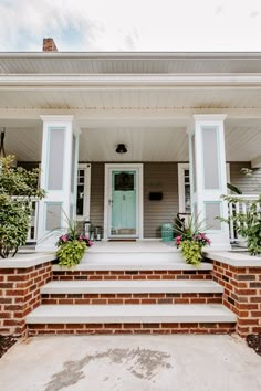 the front porch of a house with flowers and potted plants on the steps leading up to it