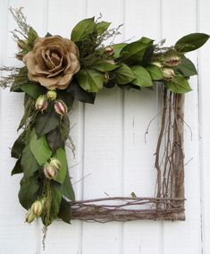 a wreath with flowers and greenery hanging on a white wall, in front of a door