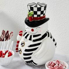 a snowman made out of candy canes sitting next to a bowl of lollipops