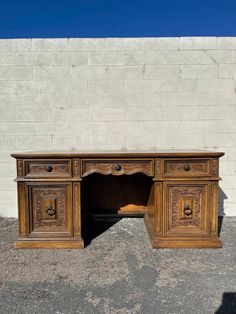 an old wooden desk sitting in front of a white brick wall with carvings on it