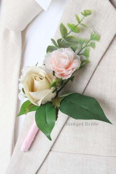 a boutonniere with two roses and greenery on the lapel of a suit