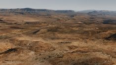 an aerial view of the desert with mountains in the background