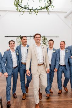 a group of men standing next to each other on top of a hard wood floor