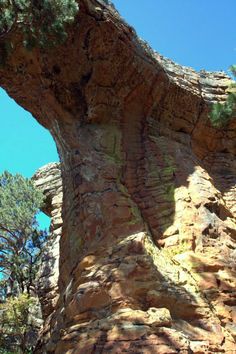 a large rock formation with trees growing on it's sides and the sky in the background