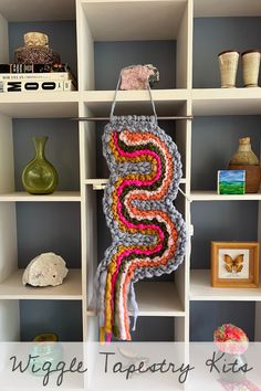 a crocheted sign hanging on a book shelf next to other books and vases